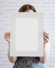 Woman holding a blank poster on wall background