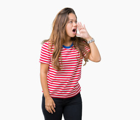 Young beautiful brunette woman wearing stripes t-shirt over isolated background shouting and screaming loud to side with hand on mouth. Communication concept.