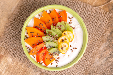 Acai bowl with vanilla smoothie, persimmon, kiwi, kumquat and flaxseeds