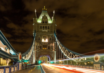 Fototapeta na wymiar Tower Bridge in London, UK at night with moving red double-decker bus leaving light traces
