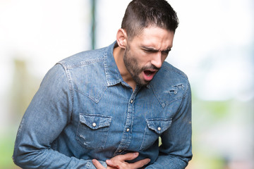 Obraz premium Young handsome man over isolated background with hand on stomach because indigestion, painful illness feeling unwell. Ache concept.