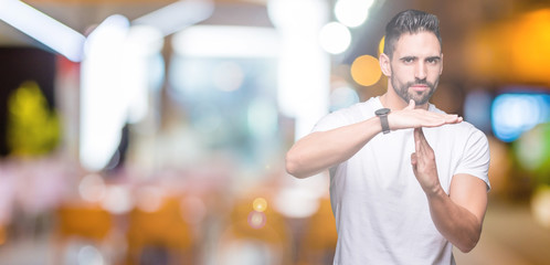 Handsome man wearing white t-shirt over night outdoors background Doing time out gesture with...