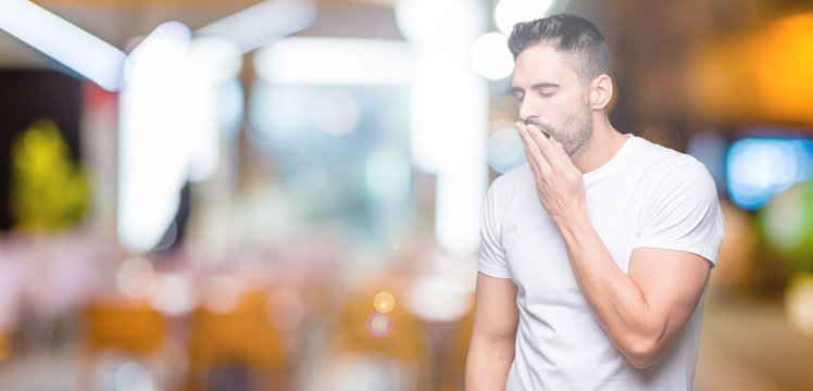 Young man wearing casual white t-shirt over isolated background bored yawning tired covering mouth with hand. Restless and sleepiness.