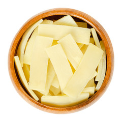 Bamboo shoots in wooden bowl. Canned slices of bamboo sprouts, used as vegetable in Asian dishes. Isolated macro food photo closeup from above on white background.