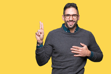 Young handsome man wearing glasses over isolated background Swearing with hand on chest and...