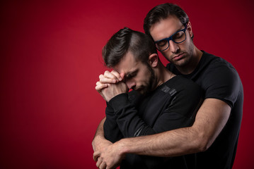 Gay couple going through rough times, comforting each other, experiencing quiet sadness