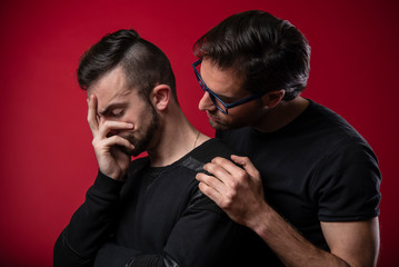 Gay couple going through rough times, comforting each other, experiencing quiet sadness