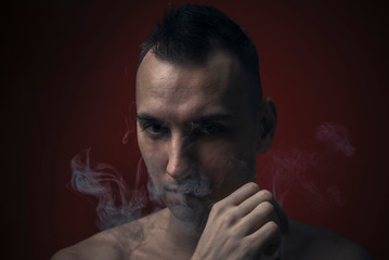 Young man inhaling a rich cloud of smoke, studio image