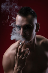Young man inhaling a rich cloud of smoke, studio image