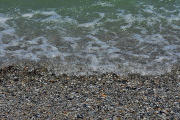 Pebbles,shells , sunlight and ripple patterns on the sea