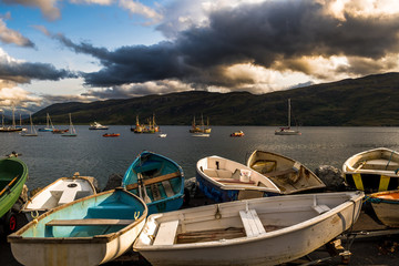 Old Small Rowing Boats At Loch Broom With Vintage Fisher Boats In The Harbor Of Ullapool In Scotland