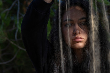 Retrato de mujer joven en primer plano derramando arena por delante de su cara