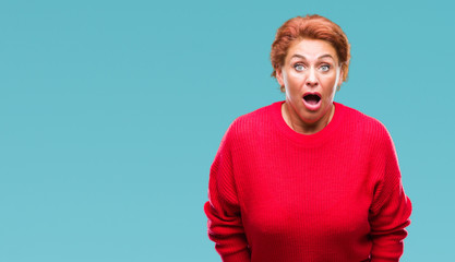 Atrractive senior caucasian redhead woman wearing winter sweater over isolated background afraid and shocked with surprise expression, fear and excited face.