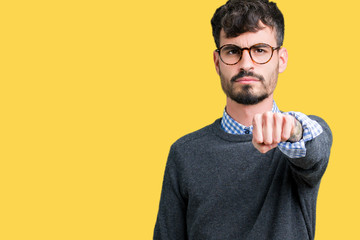 Young handsome smart man wearing glasses over isolated background Punching fist to fight, aggressive and angry attack, threat and violence