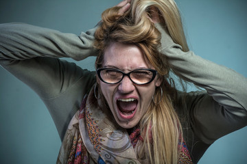 Angry frustrated woman screaming like crazy and pulling her hair