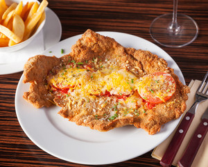 Top view of a baked schnitzel milanese - beautifully arranged and served on a wooden table