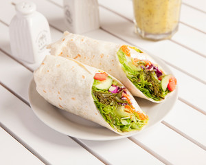 Vegan wrap, beautifully arranged and surved on a white wooden table