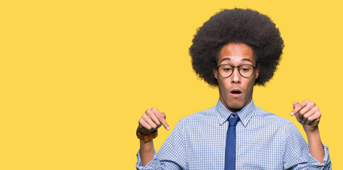Young african american business man with afro hair wearing glasses Pointing down with fingers showing advertisement, surprised face and open mouth