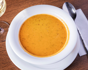 Delicious lentil soup served in a white plate on a wooden table