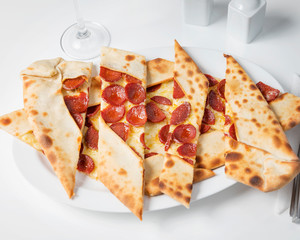 Turkish pide with salami sausage, beautifully arranged on a white table background