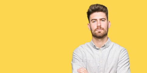 Young handsome man wearing casual shirt skeptic and nervous, disapproving expression on face with crossed arms. Negative person.