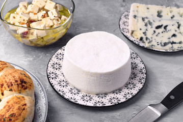 natural goat cheese and other types of cheese on gray marbled background