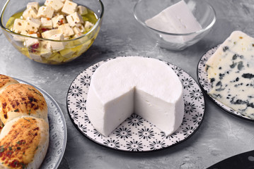 natural goat cheese and other types of cheese on gray marbled background