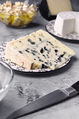 piece of roquefort cheese and other types of cheese on gray marbled background