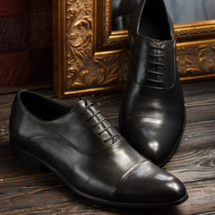 Black oxford shoes with golden picture frame on dark wooden background