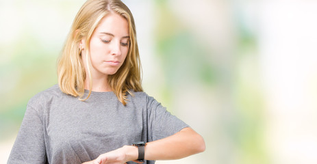 Beautiful young woman wearing oversize casual t-shirt over isolated background Checking the time on...