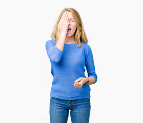 Beautiful young woman wearing blue sweater over isolated background Yawning tired covering half face, eye and mouth with hand. Face hurts in pain.