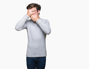 Young handsome man wearing winter sweater over isolated background Covering eyes and mouth with hands, surprised and shocked. Hiding emotion