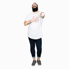 Young hipster man with long hair and beard wearing casual white t-shirt Laughing of you, pointing to the camera with finger hand over chest, shame expression