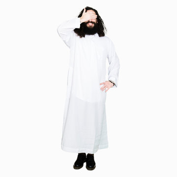 Man wearing Jesus Christ costume smiling and laughing with hand on face covering eyes for surprise. Blind concept.