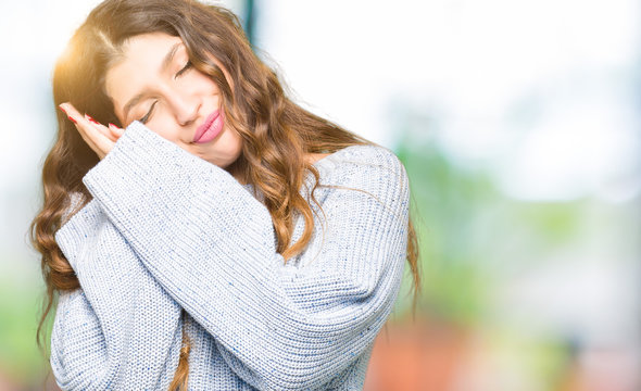 Young beautiful woman wearing winter sweater sleeping tired dreaming and posing with hands together while smiling with closed eyes.
