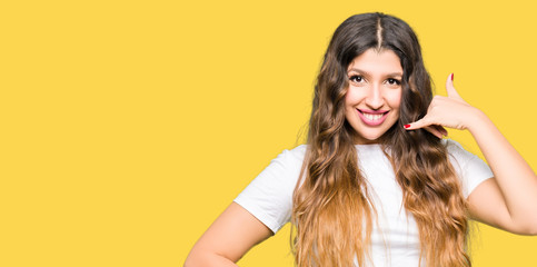 Young beautiful woman wearing casual white t-shirt smiling doing phone gesture with hand and fingers like talking on the telephone. Communicating concepts.