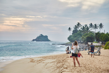 girl taking pictures of the sunset. Midigama Beach. Sunset in the Indian ocean. Midigama, Sri Lanka