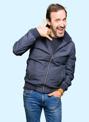 Middle age handsome man wearing a jacket smiling doing phone gesture with hand and fingers like talking on the telephone. Communicating concepts.