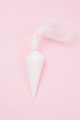 Close up of colored piping bag with pink  frosting inside opened and used over a pink background