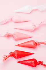 Close up of colored piping bag with pink  frosting inside opened and used over a pink background