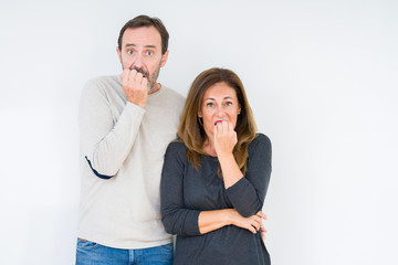 Beautiful middle age couple in love over isolated background looking stressed and nervous with hands on mouth biting nails. Anxiety problem.