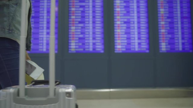 Slow motion - Happy Asian woman looking at information board checking her flight with luggage in terminal hall at the departure gate in international airport. Lifestyle women happy in airport concept.
