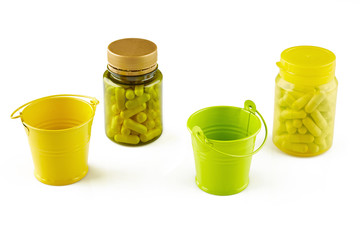 Colorful bottles with pills and two buckets. Isolated on white background