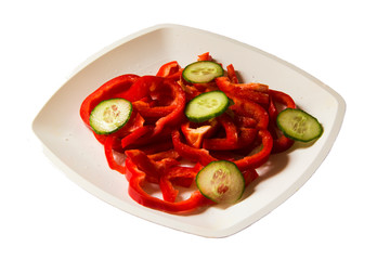 White plate with a large chopped sweet pepper and cucumber on a white background