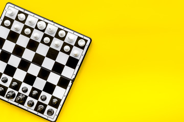 Chess game concept. Chess board with figures on yellow background top view space for text