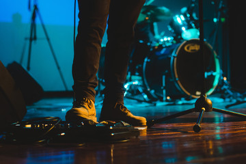 pedal de guitarra con pie con una bota de cuero en concierto sobre una tarima  