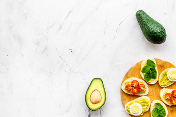 Healthy snacks. Set of toasts with vegetables like avocado, guacamole, rocket, cherry tomatoes on white stone background top view space for text