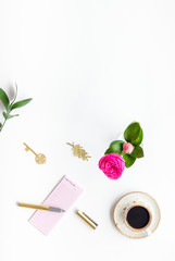 Home work desk, feminine workplace. Notebook and stationery near pink flowers and coffee on white background top view copy space