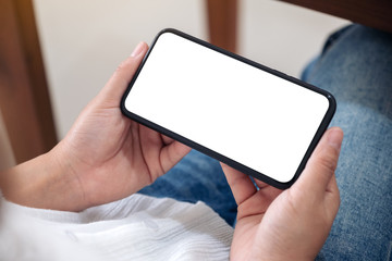 Mockup image of a woman holding black mobile phone with blank desktop screen horizontally while...