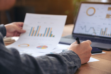A businesswoman writing and working on business data and document with laptop on the table in office